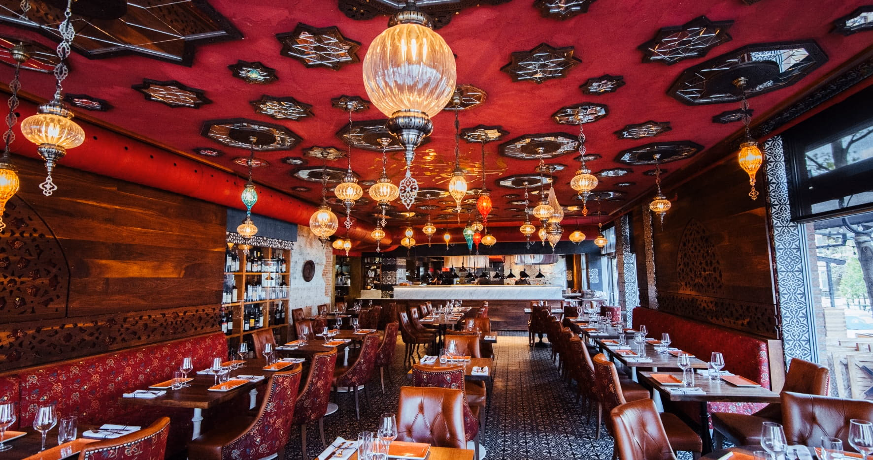 La salle du restaurant Damas : plafond de velours rouge, lanternes de verre soufflé et boiseries sculptées.